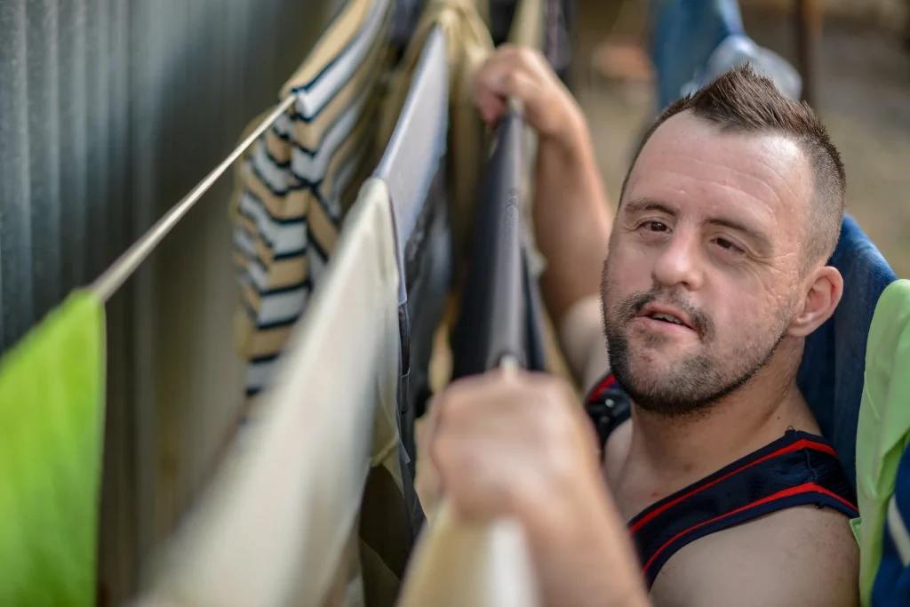 disabled men with down syndrome putting clothes on rope to dry
